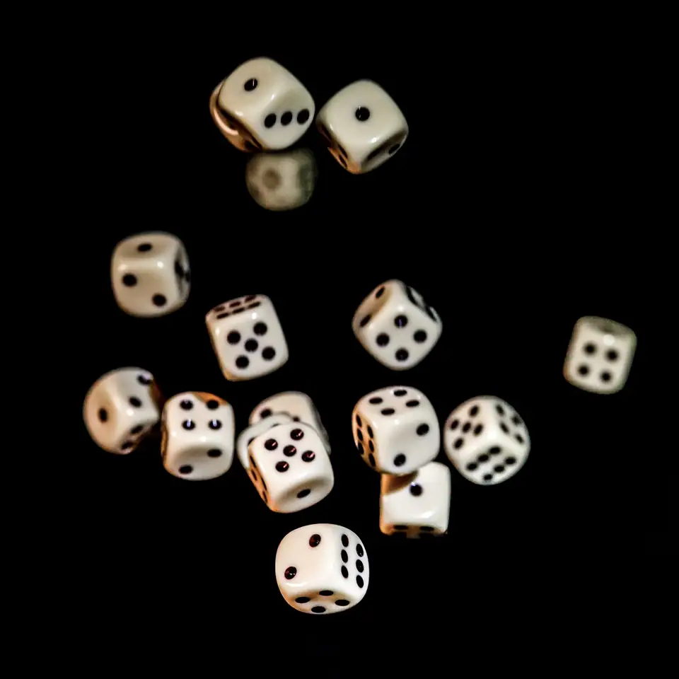 White six-sided dice tumbling through the air against a black background