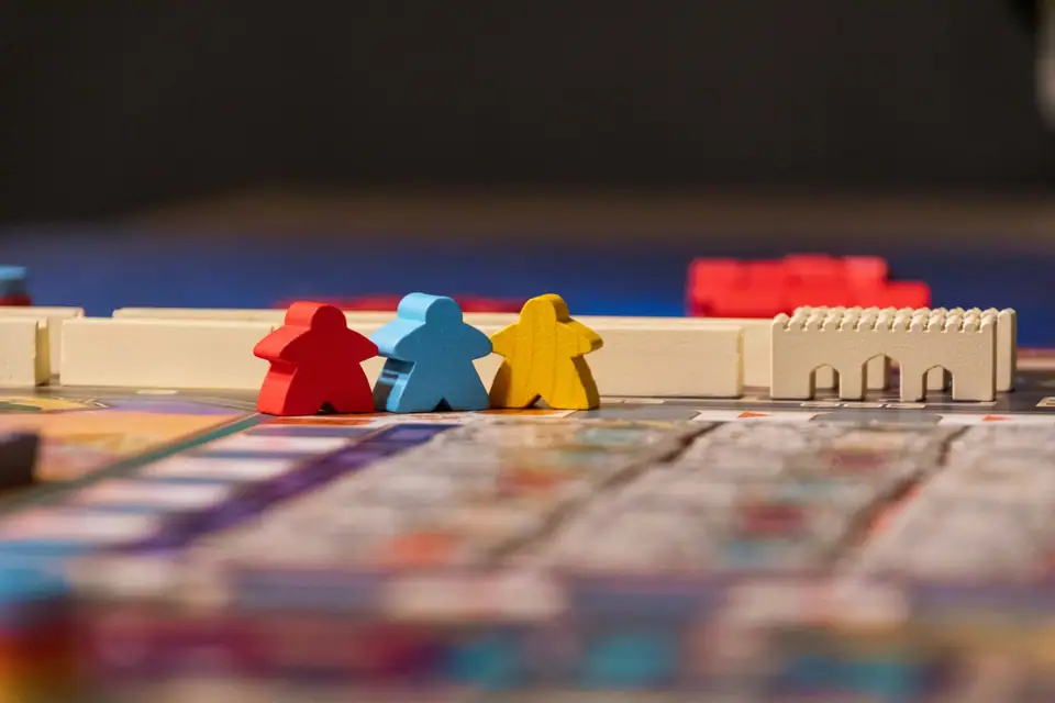 Red, blue and yellow wooden meeples standing on a game board